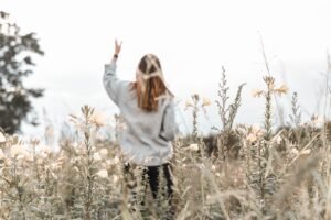 woman in white sweater standing on brown grass field during daytime